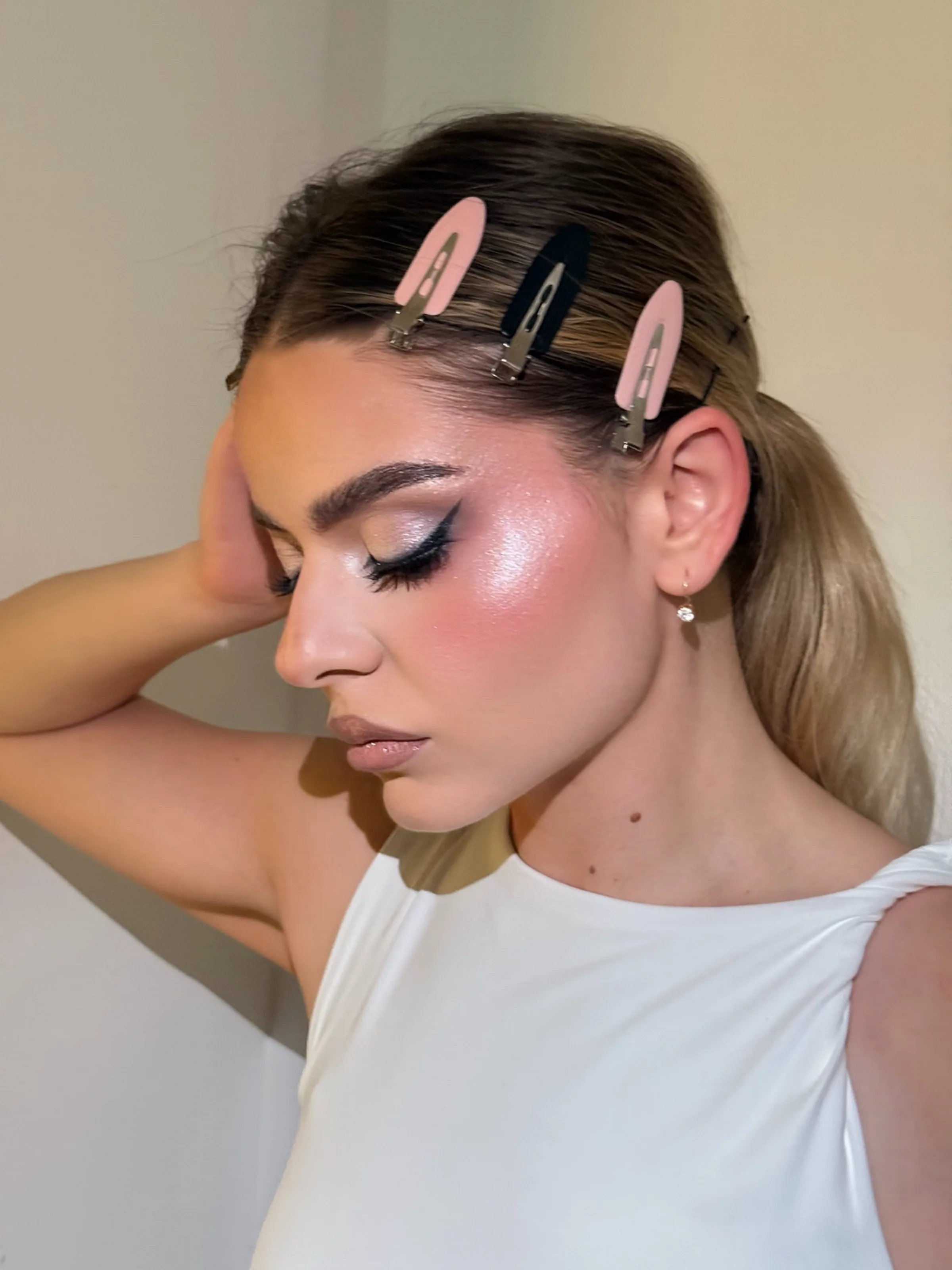 High-shine glam with a smoked black wing, pearlescent highlight along the cheekbone and a soft nude lip.